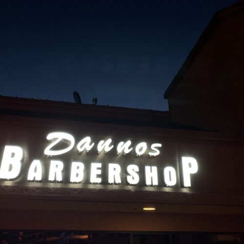 1. A sign reading "Dannos Barber Shop" illuminated at night.